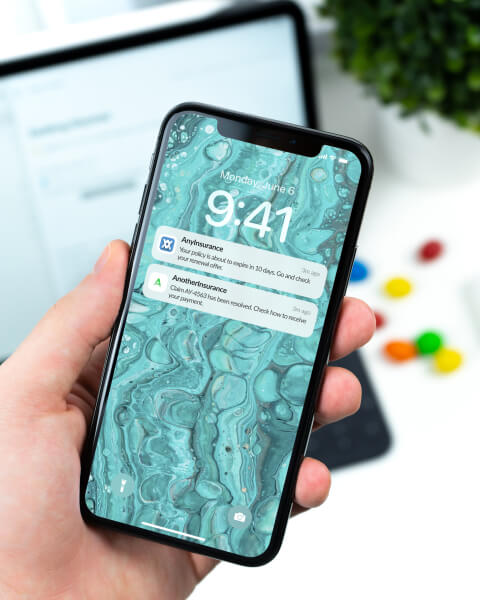 A hand holding an iPhone with reminders on screen